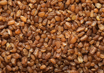 Wall Mural - Brown raw healthy bulgur grain seeds textured background.Macro.