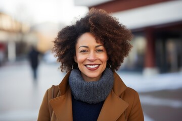 Wall Mural - Portrait of a cheerful afro-american woman in her 40s dressed in a warm wool sweater while standing against modern university campus background