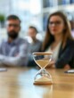 © MEHDI - an hourglass on a table and background with blurred people during a job interview meeting