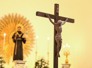 Blurred religious statue in background of church with wooden crucifix, symbolizing faith, spirituality, and christianity