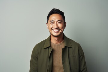 Poster - Portrait of a happy asian man in his 30s wearing a chic cardigan isolated in minimalist or empty room background