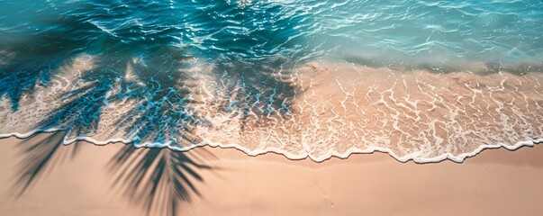 Wall Mural - Turquoise ocean water is creating white foam on a sandy beach with palm tree shadows