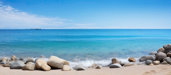Pile of rocks on the beach with a beautiful blue sea view during the day in a blurry view. Creative banner. Copyspace image