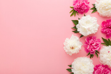 Wall Mural - Fresh beautiful soft white pink peony flowers with green leaves on light pink table background. Pastel color. Closeup. Empty place for inspirational text, lovely quote or sayings. Top down view.