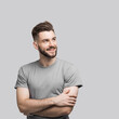 © kite_rin - Portrait of handsome smiling young man looking up isolated on gray background. Laughing joyful cheerful men with folded arms studio shot