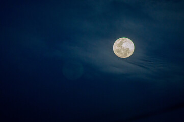 The moon is shining brightly with clouds in the night sky.