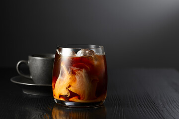 Poster - Iced coffee with cream and cup of black coffee on a black wooden table.