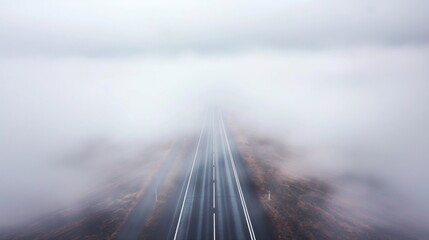 Wall Mural - A long, straight road on a foggy morning, with the road disappearing into the white mist, creating a mysterious atmosphere.