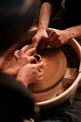 Potter teaching woman to craft ceramic jug on a pottery wheel