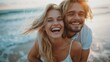 © LukaszDesign - Closeup portrait of young couple smiling, hugging, and enjoying a beach day with ocean in backdrop. Vacationing romantic pair. Guy carrying blonde wife