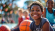 © khonkangrua - A cheerful boy holding a basketball outdoors, surrounded by friends, enjoying a sunny day on the playground.
