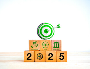 Wall Mural - Happy new year 2025 with ESG business and technology concept. Green 3d target dart icon on on wooden cube blocks stack with 2025 numbers and ESG icons, isolated on wood table and white background.