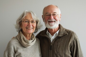 Wall Mural - Portrait of a grinning caucasian couple in their 80s showing off a thermal merino wool top in front of bare monochromatic room