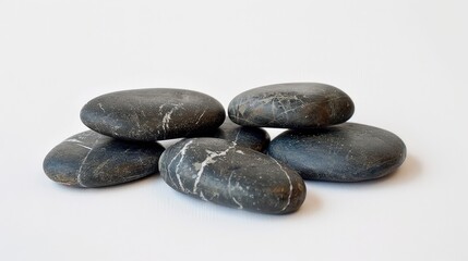 Spa hot stones arranged in a pile against a white backdrop