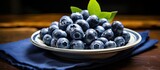 A bunch of ripe vaccinium corymbosum with black skin and a sweet taste are on a small plate in the kitchen. Creative banner. Copyspace image