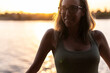 © Manu Prats - Self-steem woman in glasses by river at sunset, thoughtful expression