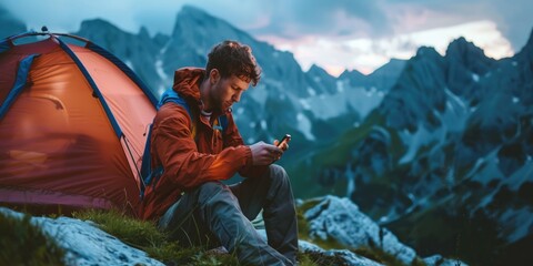 Wall Mural - A person examining their smartphone near a camping tent