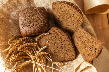 Borodinsky rye bread with thyme in a basket with ears of barley on a canvas cloth,