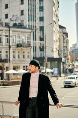 Wall Mural - Red-haired man in debonair black coat and hat leaning on rail.