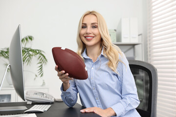 Wall Mural - Happy woman with american football ball at table in office