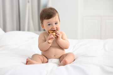 Canvas Print - Cute baby boy with wooden rattle on bed at home