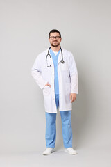 Canvas Print - Full length portrait of smiling doctor on light grey background