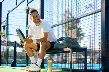 Happy athlete relaxing after playing paddle tennis outdoors.