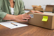 © olga_demina - Hands of female consumer stick barcode on cardboard box with yellow sticker with word Return sitting at workplace with statement concept of returning parcel