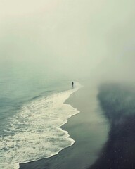 Wall Mural - A person is walking on a beach with a foggy sky in the background