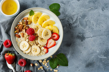 Wall Mural - A bowl of fruit and oatmeal with bananas and raspberries. The bowl is on a table with a spoon and a cup of honey
