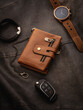 © Vitte Yevhen - Luxury brown wallet with chain, elegant wristwatch, and stylish bracelet and car key fob arranged on rich dark textured leather surface. Mens essentials concept