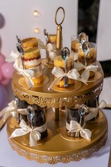 Wall Mural - Display of layered dessert cups with spoons tied with ribbons on a gold tiered stand