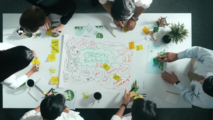 Top down view of business team discussing about using clean energy and sustainable investment at meeting table with wind mill, document with environmental graph and wooden house model. Alimentation.