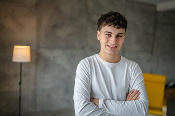 Portrait of one caucasian man 20 years old looking to the camera at home smiling wearing casual white shirt copy space