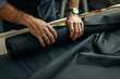 © master old - Man couturier is straightening a roll of black fabric.