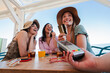 © Jose Calsina - Happy young group of only women paying the bill with a contactless credit card in cocktail beach bar. Female smiling holding a creditcard and giving a payment transaction to the cashier on vacations