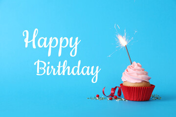 Wall Mural - Birthday cupcake with sparkler on light blue background. Greeting card