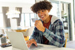 © Wavebreak Media - Happy biracial man holding credit card while using laptop, shopping online