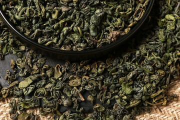 Wall Mural - Tray with green tea leaves and sackcloth as background