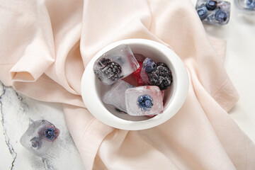 Wall Mural - Bowl with frozen berries in ice cubes on white background