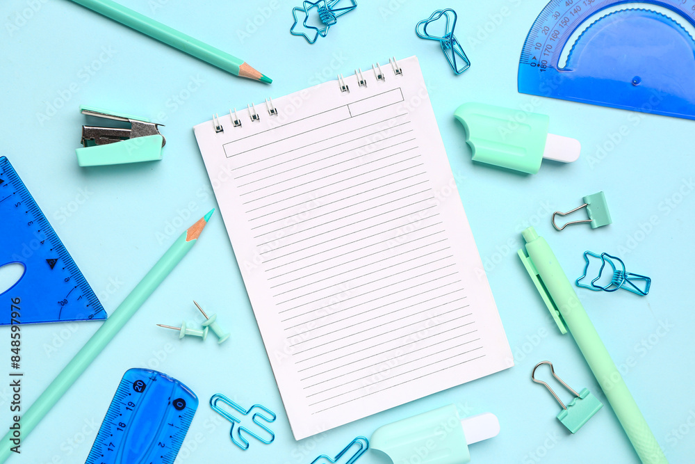 Notebook with different stationery supplies on blue background