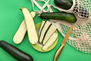 Wall Mural - Fresh zucchini in string bag and plate with slices on green background