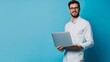 © Pro Hi-Res - Smiling man holding laptop against blue background.