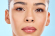 © peopleimages.com - Close up, skincare and portrait of model girl in studio for beauty, glow and wellness or cosmetics. Woman, laser and results for dermatology or chemical peel by blue background with shine from facial