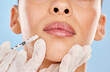 © peopleimages.com - Woman, mouth and needle in hand for plastic surgery with anti aging results and medical process in studio. Female client, cosmetic change and closeup injection with filler for lips by blue background