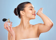 © Alexis S/peopleimages.com - Perfume, fragrance and woman with wrist smell for clean scent and beauty salon aesthetic in studio. Wellness, model girl and parfum bottle with spray skin for self care and fresh by blue background
