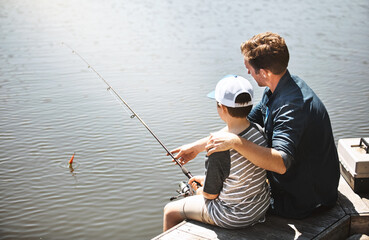 Wall Mural - Father, back and teaching with son for fishing with rod by lake, ocean or beach together in nature. Dad with child, young kid or little boy with hug for bonding lesson or tips to catch by water