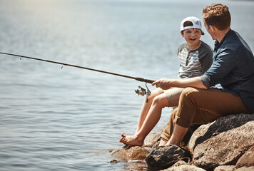 Wall Mural - Happy child, father and learning with fishing rod by lake, ocean or beach together in nature. Dad with son, young kid or little boy for bonding, teaching tips or lesson to catch by sea water