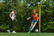 © master1305 - Dynamic Sports Coaching. Girl in colorful soccer uniform demonstrating her dribbling skills, playing football with guidance of female coach. Concept of sport, school, childhood, active lifestyle