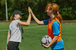 © master1305 - Female soccer coach giving high five to girl, football player after producing outdoor game session on outdoor arena. Concept of sport, school, childhood, hobby, active lifestyle